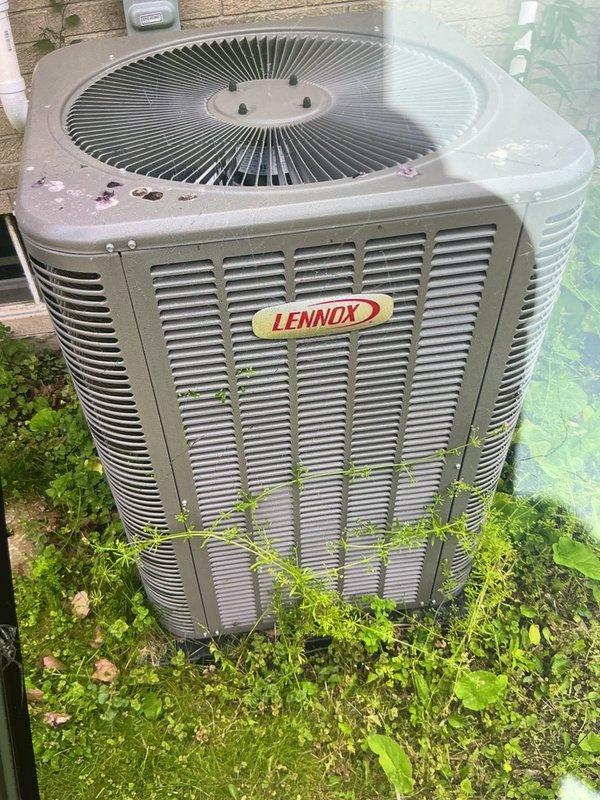 Responded to service call for Lennox outdoor condensing unit experiencing abnormal noise during operation. Performed comprehensive Air Conditioning Maintenance (ACM) on one-year-old system under parts and labor warranty. Inspected condenser unit, cleared vegetation growth from base and around lower louvers, verified fan operation and electrical connections, and documented equipment condition with photographic evidence of unit exterior and installation location.