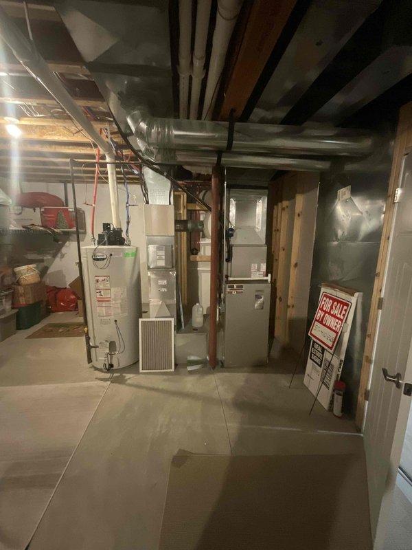 Conducted on-site assessment for complete air conditioning system replacement. Evaluated existing 15-year-old outdoor condensing unit positioned on concrete pad adjacent to building exterior, noting unit's age and operational history. Inspected indoor air handler located in basement mechanical room alongside existing water heater and ductwork infrastructure. Documented current system configuration including refrigerant line routing through exterior conduit, electrical connections, and existing ductwork distribution throughout the space. Photographed equipment specifications, model information, and installation conditions to prepare comprehensive replacement quote for new AC system installation scheduled within the month.