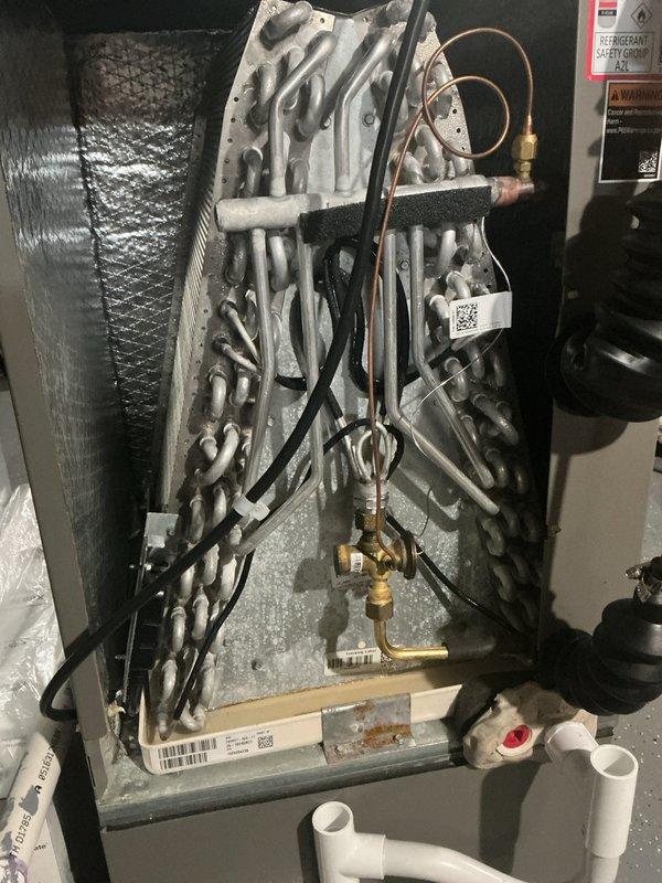 Performed annual cooling maintenance on HVAC system. Upon inspection, discovered evaporator coil completely frozen with heavy ice buildup across entire surface, indicating restricted airflow or low refrigerant charge. Identified cause as severely restricted airflow due to dirty/clogged filter media. Shut down system to allow coil to thaw completely. Replaced furnace filter as requested. Inspected condensate drain system and PVC drain lines for proper operation. Checked refrigerant lines, service valves, and brass fittings for leaks or damage. Once coil thawed, verified drain pan functionality and cleared any residual moisture. Reinstalled access panel and restored system to normal operation. Advised monitoring system performance to ensure ice buildup does not recur. System operating within normal parameters upon departure.