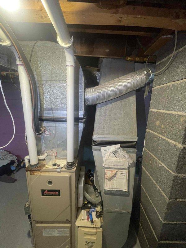 Completed comprehensive assessment of 26-year-old Amana furnace and air conditioning system for full replacement estimate. Documented existing basement installation including dual furnace configuration, Aprilaire Model 2401 high efficiency air cleaner, PVC venting system, and outdoor condensing unit. Photographed current equipment condition, ductwork layout, and mechanical room configuration to provide accurate replacement specifications for expedited system upgrade.