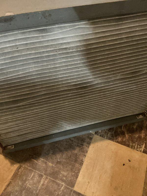 Completed annual HVAC maintenance service on wall-mounted air handler unit in basement mechanical room. Inspected system components, accessed filter compartment, verified proper operation of condensate drain lines, and documented equipment condition with photos showing accumulated dust on unit exterior and mesh filter assembly.
