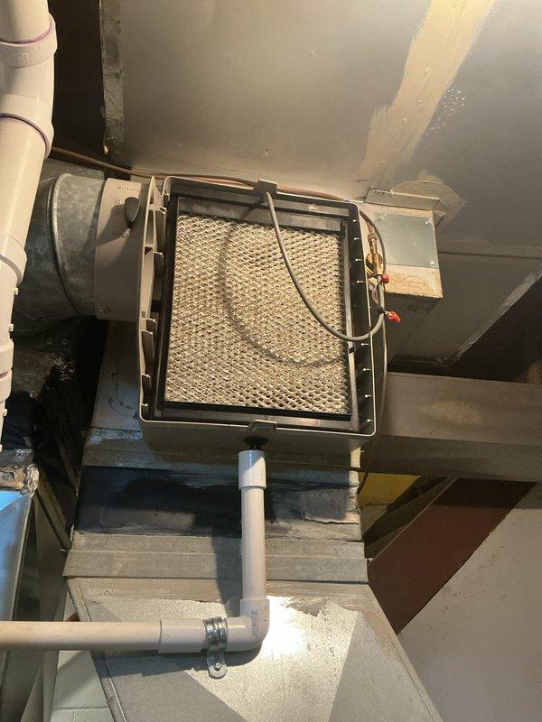 Completed annual HVAC maintenance service on wall-mounted air handler unit in basement mechanical room. Inspected system components, accessed filter compartment, verified proper operation of condensate drain lines, and documented equipment condition with photos showing accumulated dust on unit exterior and mesh filter assembly.