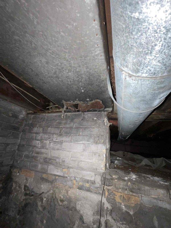 Conducted site assessment for ductwork modification quote following handoff from field technicians. Evaluated existing HVAC system with 6-ton blower unit serving 135 BTU load. Inspected multiple return air vents throughout residence that had been previously covered or sealed. Documented double return vent location at interior entryway requiring restoration to proper airflow configuration. Accessed crawlspace to examine existing ductwork infrastructure, including galvanized metal supply ducts and insulated return air plenums supported above foundation. Photographed current duct routing, connections, and structural conditions to develop comprehensive scope of work for reopening sealed return vents and restoring proper system air balance.