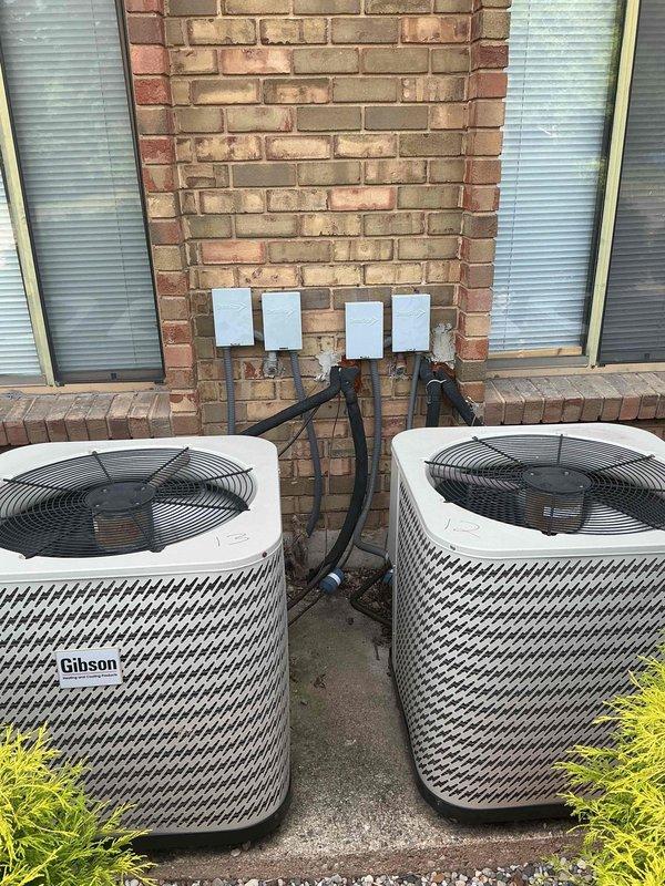 Responded to no cooling complaint for multiple Gibson-branded air conditioning units over 20 years old. Upon arrival, found four condenser units installed on concrete pad with gravel base against building exterior. Performed visual inspection of all units, checking refrigerant line connections, electrical conduits, and overall equipment condition. Documented existing equipment configuration showing two pairs of units with black refrigerant lines routed up brick wall and standard wire fan guards in place. Units exhibited age-appropriate wear consistent with 20+ year service life. Given the advanced age of the equipment and no cooling condition, advised customer that these systems have exceeded their typical 15-year lifespan and replacement would be more cost-effective than repair. Photographed installation for documentation purposes showing equipment layout, mounting configuration, and connection points. Customer provided contact information for follow-up consultation regarding replacem