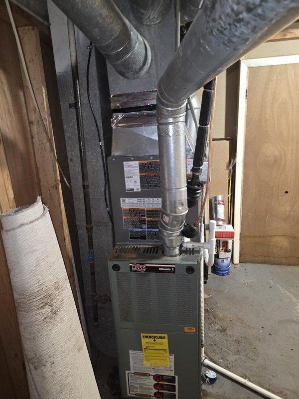 Completed installation of 2-ton air conditioning system with evaporator coil. Installed Ruud furnace unit in basement mechanical space with proper supply and return ductwork connections, ensuring appropriate clearances from combustible materials. Mounted outdoor condenser unit on concrete pad with electrical disconnect box, connected refrigerant lines via wall penetrations using white PVC conduit. Verified all connections, tested system operation, and confirmed proper airflow through ductwork. Installation completed per mechanical permit requirements with rear placement configuration and reconnection of existing electrical service.