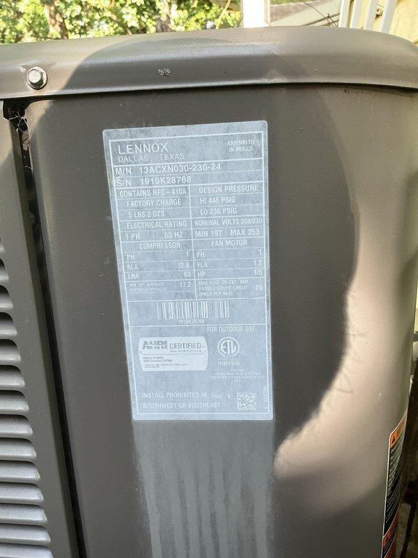Responded to service call for Lennox model 13ACXN030-230-24 air conditioning unit (serial number 1919K28788) that was reported as turning on. Performed diagnostic inspection of 6-year-old outdoor condensing unit containing R-410A refrigerant with factory charge of 5 lbs 2 oz. Inspected unit exterior, verified proper condensate drainage through white flexible drain line, checked electrical connections and conduit at unit base, and documented equipment specifications and current operating condition. Unit found to be functioning as designed with no immediate repairs required at time of inspection.