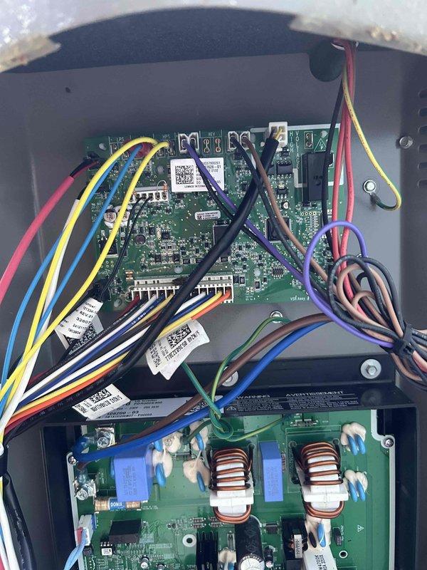 Responded to callback for Lennox air conditioning system displaying "service urgent" message on thermostat with unit not operating. Upon arrival, inspected 5-year-old outdoor condenser unit and accessed control board compartment. Diagnosed control board issue related to safety lockout condition. Inspected dual circuit board assembly including upper control board with integrated circuits and wiring harness connections, and lower board containing toroidal inductors. Cleared fault code, verified all wire connections at terminal blocks were secure, and tested system operation. Unit restored to normal cooling operation with thermostat error message cleared and all safety controls functioning properly.