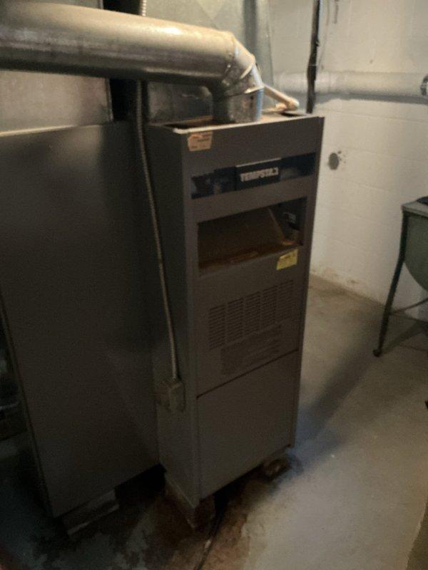 Responded to service call for water leaking from 38-year-old furnace located in basement. Upon inspection, observed visible water staining and discoloration on concrete floor surrounding base of unit, confirming active leak condition. Documented existing HVAC installation including furnace cabinet, metallic ductwork system with flexible and rigid connections, gas line with shutoff valve, and associated mechanical components. Given the advanced age of the equipment and absence of warranty coverage, provided assessment and recommendations for addressing the water leak issue.