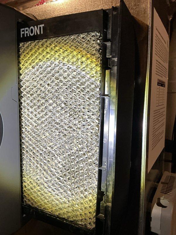 Performed routine air conditioning maintenance inspection on residential HVAC system. Accessed unit through front panel in utility space, inspected existing air filter which showed significant dust accumulation and discoloration. Replaced dirty pleated air filter with new filter featuring proper MERV rating and directional airflow indicators to ensure optimal system performance and indoor air quality.
