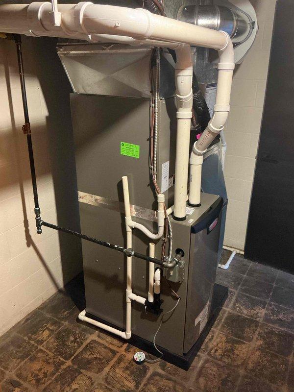 Completed full HVAC system installation including new furnace and air conditioning unit in utility space. Installed gray metal furnace with proper condensate drainage system using white PVC piping, routed supply and return ductwork, and connected all necessary plumbing lines including copper refrigerant lines. All ventilation lines properly secured with mounting brackets, condensate pump installed and operational, system tested and verified for proper operation with permits requested prior to installation.