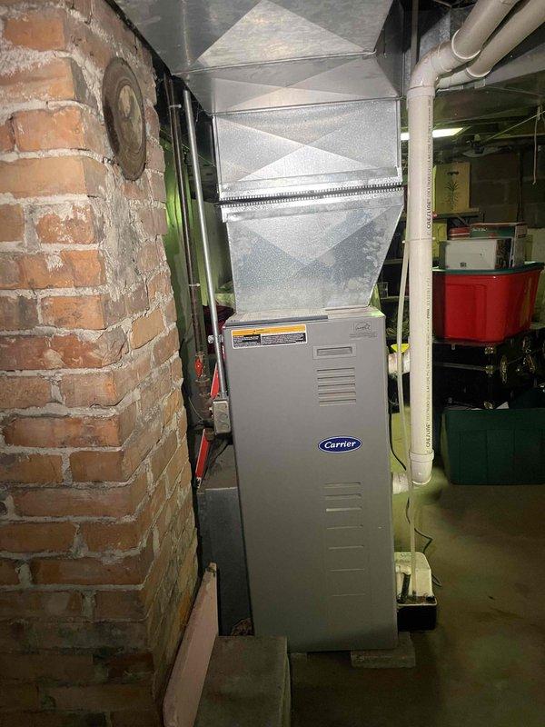 Conducted on-site assessment of existing Carrier furnace system in basement of single-family residence to provide estimate for full-house ducted heat pump replacement. Current system includes aging furnace with unknown service history at risk of failure within next few years, with no existing air conditioning capability. Evaluated existing ductwork configuration, basement installation space, and structural considerations including exposed brick walls and concrete foundation. Documented current equipment layout, condensate drainage system with white PVC piping, and plenum connections to determine compatibility with proposed heat pump system. Photographed existing Carrier furnace unit, air handler, ductwork transitions, and available installation area to develop comprehensive replacement quote for whole-house heating and cooling solution. Customer seeking options for system upgrade within two to six month timeline with no immediate operational concerns.