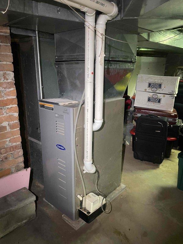 Conducted on-site assessment of existing Carrier furnace system in basement of single-family residence to provide estimate for full-house ducted heat pump replacement. Current system includes aging furnace with unknown service history at risk of failure within next few years, with no existing air conditioning capability. Evaluated existing ductwork configuration, basement installation space, and structural considerations including exposed brick walls and concrete foundation. Documented current equipment layout, condensate drainage system with white PVC piping, and plenum connections to determine compatibility with proposed heat pump system. Photographed existing Carrier furnace unit, air handler, ductwork transitions, and available installation area to develop comprehensive replacement quote for whole-house heating and cooling solution. Customer seeking options for system upgrade within two to six month timeline with no immediate operational concerns.