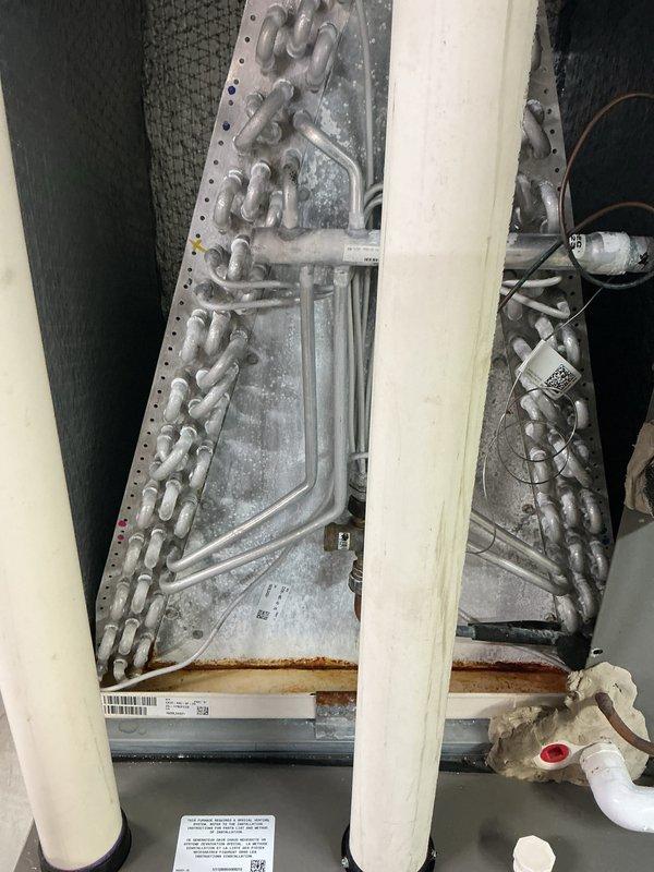 Completed routine seasonal air conditioning maintenance on 5-year-old residential system with Lennox furnace. Inspected evaporator coil and discovered significant frost and ice buildup on serpentine coils, along with rust staining on drip pan indicating potential drainage or airflow issues. Documented system condition with photos showing refrigerant lines, ductwork, electrical connections, and coil deterioration for future reference and recommended follow-up maintenance.