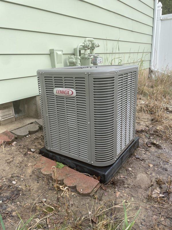 Completed annual cooling maintenance on Lennox outdoor condensing unit. Performed comprehensive system inspection including electrical connections, refrigerant line assessment, and condenser coil evaluation. Unit found operating within normal parameters. Verified proper placement on pad and confirmed all refrigerant lines and electrical connections secure. Documented equipment condition with photos showing unit positioned on black composite pad against building exterior with copper refrigerant lines properly routed to structure.