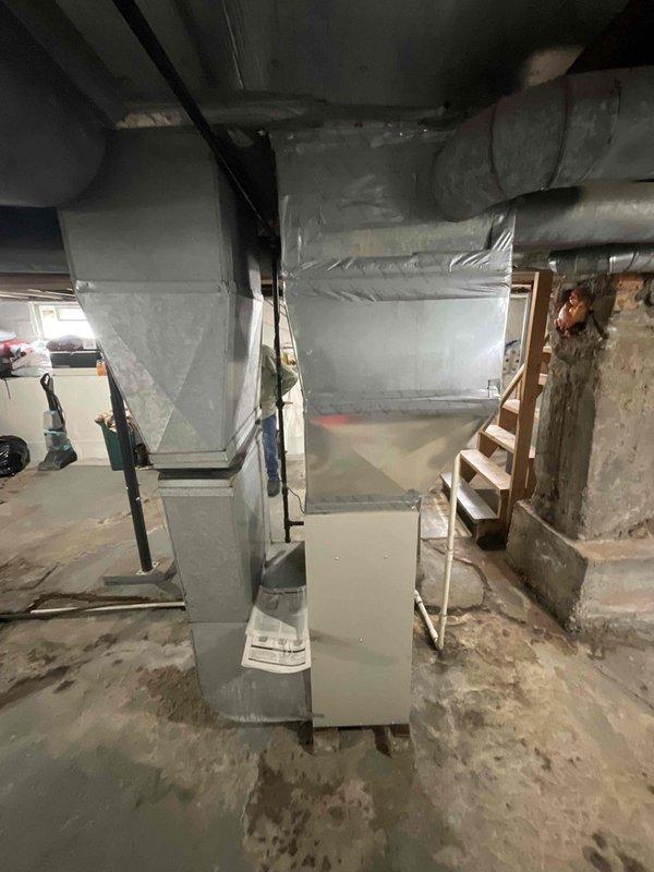 Responded to service call for air conditioning system with reported performance concerns. Upon arrival, performed comprehensive system evaluation of 6-year-old AC unit and furnace installation. Conducted thorough inspection of basement mechanical room, examining furnace cabinet, ductwork connections, and overall HVAC infrastructure. Assessed water heater proximity and clearances to mechanical equipment. Evaluated supply and return air duct configuration, including wrapped insulation integrity. Inspected furnace mounting, support straps, and structural installation. Reviewed system age, condition, and operational parameters. Presented full system replacement estimate to address performance concerns and aging equipment. Documented existing equipment configuration with photographic records of current mechanical room layout, furnace positioning, ductwork routing, and utility connections for replacement planning purposes.