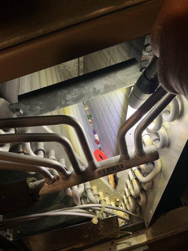 Completed annual HVAC maintenance visit including system inspection and filter replacement. Accessed heat exchanger compartment to inspect coils and internal components, documenting conditions with photos showing parallel heat exchanger tubes and refrigerant lines in operational condition with normal signs of age and wear. Replaced air filter and verified proper system operation upon completion.