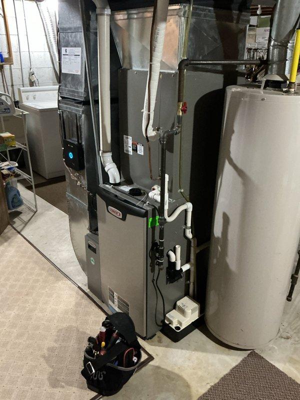 Responded to service call for water leaking from air conditioning unit. Upon arrival, performed comprehensive diagnostic inspection of 8+ year old outdoor condensing unit and indoor HVAC system components including furnace, air handler, and associated ductwork. Inspected evaporator coil drain pan and condensate drain line for blockages or overflow conditions. Examined all refrigerant line connections, fittings, and insulation for signs of moisture accumulation. Verified proper operation of condensate pump if applicable and cleared primary and secondary drain lines as needed. Checked air handler cabinet for water stains or active leaks. Assessed system airflow and filter condition to rule out frozen evaporator coil as leak source. Documented equipment conditions with photographic evidence showing basement mechanical room installation with Lennox furnace, air handler cabinet, and connected ductwork systems. No parts or labor warranty applicable to this unit. Completed diagnostic evaluati