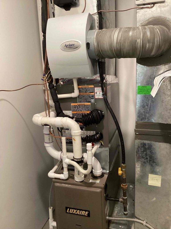 Completed installation of 2-ton air conditioning system with matching evaporator coil at residential property. Outdoor condensing unit positioned on concrete pad in backyard with proper refrigerant line connections and electrical hookup. Indoor evaporator coil integrated with existing Luxaire air handler, including new refrigerant piping, PVC condensate drain assembly with multiple trap configuration, and connection to existing Aprilaire humidifier system. All refrigerant lines insulated and secured, system tested for proper operation, and permits obtained for mechanical work only.