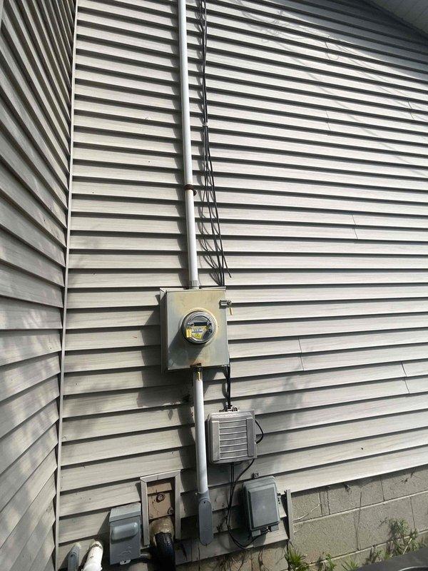 Conducted on-site evaluation for whole house generator installation at residential property. Assessed existing electrical service infrastructure, including current meter assembly, disconnect boxes, and main electrical panel configuration. Documented current electrical setup with white vinyl-sided exterior wall mounting arrangement and PVC conduit routing. Evaluated electrical service capacity and determined requirements for generator integration, including necessary transfer switch placement, fuel line routing considerations, and optimal generator pad location. Reviewed property layout across front, side, and rear yard areas to identify suitable generator placement that meets code clearance requirements from structure and utilities.
