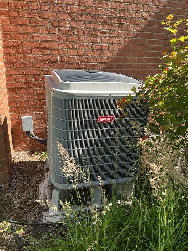 Responded to no-cooling complaint on 14-year-old Bryant central air conditioning system with malfunction message displaying on Evolution thermostat. Upon arrival, found outdoor condenser unit heavily obstructed by overgrown vegetation affecting airflow and system performance. Cleared grass, weeds, and plant growth from around condenser perimeter to restore proper ventilation. Inspected electrical connections at disconnect box and verified proper power supply to unit. Cycled system through startup sequence and confirmed thermostat communication restored with condenser now operating continuously without short-cycling. Unit resumed normal cooling operation with adequate airflow through condenser coils after vegetation removal.