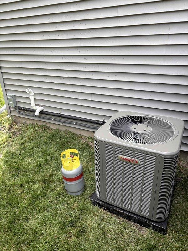 Completed full HVAC system installation including a 70,000 BTU furnace with humidifier and 3-ton air conditioning unit. Indoor equipment installed on platform base in basement with proper condensate drainage via PVC piping, flexible ductwork connections, and refrigerant line sets between units. Outdoor Lennox condenser unit positioned on pad with electrical and refrigerant connections completed to manufacturer specifications.
