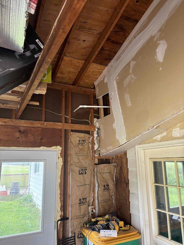 Completed ductwork modifications in residential space with exposed framing and insulation. Installation performed in area with kraft paper-faced insulation and ongoing drywall finishing work. Verified electrical system voltage at 124V during installation process to ensure proper operating conditions for HVAC system integration.