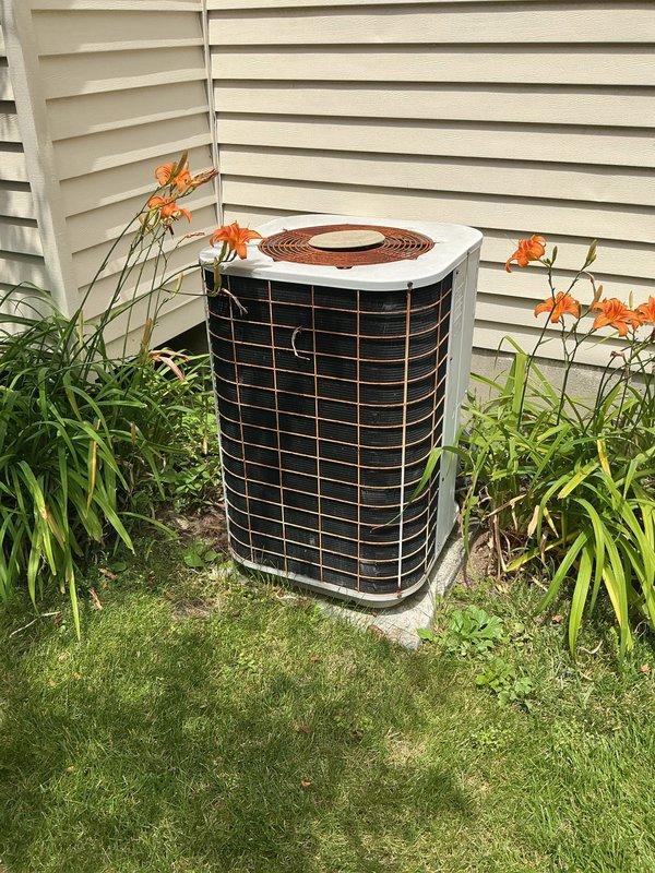 # No Cooling - 20 Year Old System

Responded to service call for AC unit running but not producing cold air affecting entire home. Upon arrival, found outdoor condensing unit operational with fan running and compressor attempting to cycle. 

Performed visual inspection of 20-year-old cylindrical condenser unit positioned on concrete pad against building exterior. Noted severely deteriorated refrigerant line insulation with multiple cracks, splits, and complete separation from copper lines in several locations. Weathered insulation exposed bare refrigerant lines to ambient temperature, resulting in significant heat gain on suction line and compromised system efficiency.

Checked electrical connections at outdoor unit - all secure with proper voltage readings. Measured temperature differential across coil and found inadequate cooling performance. Observed compressor short-cycling behavior indicating possible refrigerant charge issue or system restriction.

Given age of equipment (20 year