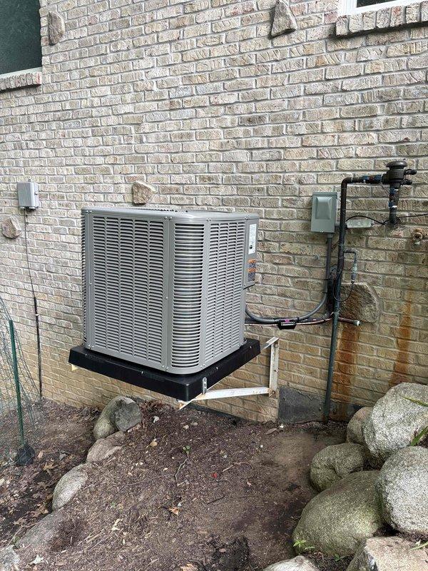 Completed full HVAC system installation including a 70,000 BTU furnace with left-side configuration, 2-ton air conditioning unit, evaporator coil, and humidifier reconnection. The outdoor condensing unit was mounted on a platform against the exterior brick wall with proper electrical conduit and refrigerant line installation. All necessary permits were obtained prior to installation, and the complete system was installed, tested, and left in proper working order.