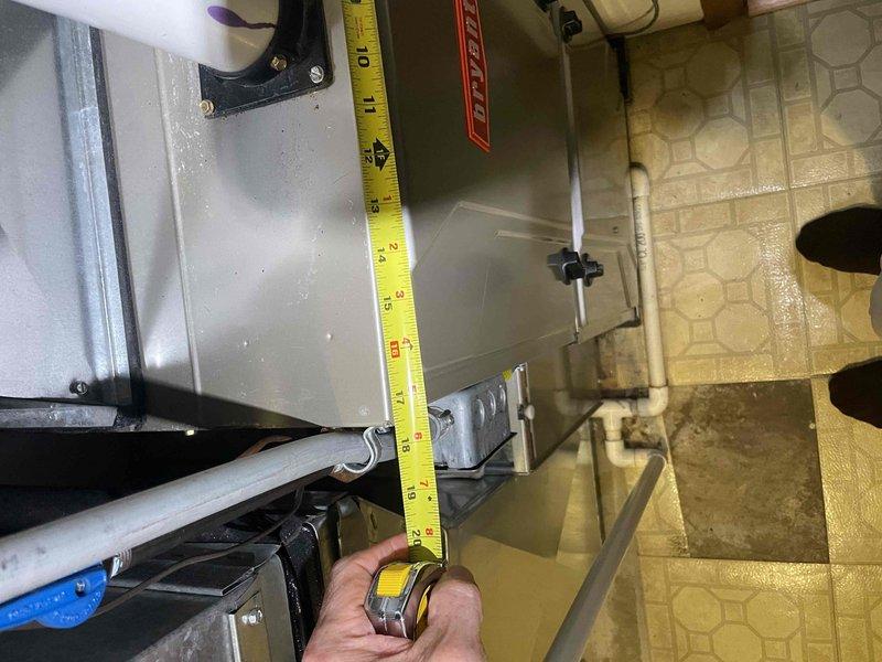Conducted on-site evaluation of 38-year-old air conditioning system for replacement estimate. Performed visual inspection and documentation of existing HVAC equipment located in mechanical utility room. Assessed current unit configuration, including condensate drainage system with white PVC piping, refrigerant line routing, and overall equipment placement within the space. Took detailed measurements of existing equipment dimensions and clearances to determine replacement unit specifications and compatibility with current installation location. Documented existing system layout, including metallic furnace housing, pipe penetrations, mounting configurations, and available workspace access on hexagonal-patterned tile flooring. Evaluated mechanical room conditions, wall penetrations, and utility connections to prepare comprehensive replacement proposal for new air conditioning system installation scheduled within customer's requested timeframe.