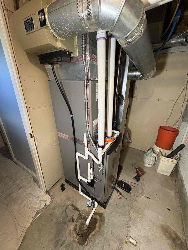 Completed full HVAC system installation including a 70,000 BTU gas furnace and 2.5 ton air conditioning unit. Installed furnace in basement mechanical room with proper venting using white PVC piping, connected all ductwork, electrical controls, and gas lines. Positioned outdoor condenser unit on gravel pad with refrigerant lines properly secured to exterior wall, evacuated and charged system to manufacturer specifications, and verified all connections and operational parameters meet code requirements.