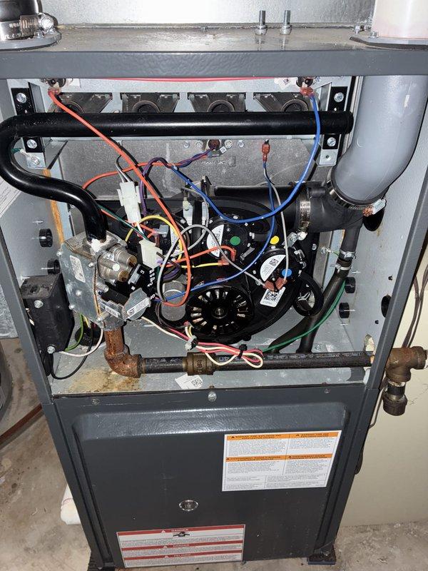 Conducted comprehensive assessment of 15-year-old residential HVAC system for complete replacement estimate due to unrepairable refrigerant leak with obsolete refrigerant type. Inspected basement-mounted gas furnace with integral blower assembly, documented existing ductwork configuration including flexible supply runs and humidifier integration, evaluated electrical connections and gas line condition showing visible oxidation on copper supply piping. Photographed outdoor condensing unit and indoor air handler components to document current system layout and specifications for accurate replacement sizing and equipment selection.