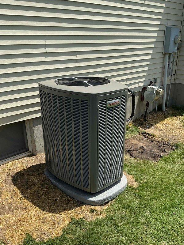 Completed full HVAC system installation including a 90,000 BTU gas furnace and 3-ton Lennox air conditioning unit with outdoor condenser positioned on concrete pad against exterior wall. Installed humidifier on left side of furnace, connected refrigerant lines with proper insulation, mounted electrical disconnect box, and reconnected all ductwork and utilities in basement mechanical room. All permits obtained, system tested and operational.