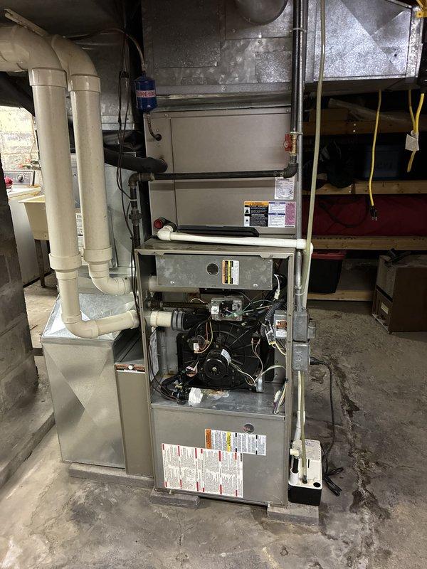 Provided estimate for complete HVAC system replacement in basement location, including both furnace and air conditioning units. Existing 20-year-old equipment showing signs of age with current unit operating marginally. Assessed existing installation including vertical furnace configuration, ductwork system, condensate drainage assembly with PVC piping, and exterior condenser location with utility connections on vinyl-sided exterior wall.