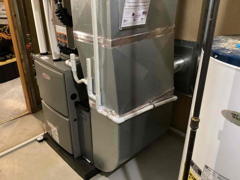 Completed full HVAC system installation including a 90,000 BTU furnace, 3.5-ton air conditioning unit with evaporator coil configured for right-side placement, and humidifier reconnection. All mechanical and electrical work performed in accordance with permit specifications, with proper PVC venting installed and ductwork connections secured to the air handler unit in basement utility area.