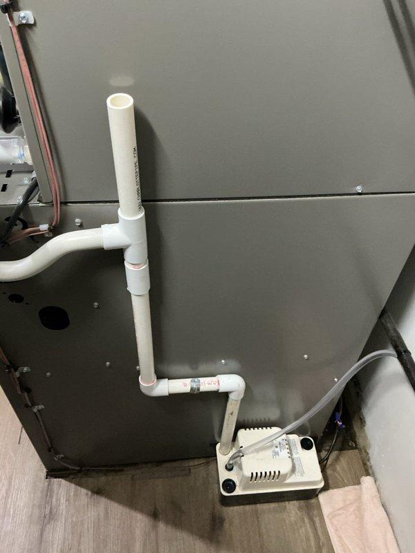 Responded to no-cooling service call for central air conditioning system less than 5 years old with unit not turning on and no fan operation. Upon arrival, discovered water leak issue affecting HVAC equipment and surrounding area, with visible moisture damage and staining on floor and wall surfaces in mechanical room. Inspected condensate drainage system including PVC piping and condensate pump assembly. Addressed water intrusion problem and restored proper system operation, ensuring condensate management components functioning correctly to prevent future leaks.