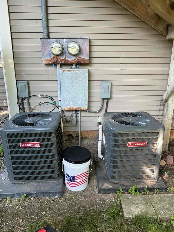 Responded to no-cool service call for dual Goodman central air conditioning system where customer reported complete loss of cooling function with only fan operation remaining. Upon arrival, performed diagnostic assessment of both 29-year-old outdoor condenser units mounted on exterior wall with shared electrical service. Conducted visual inspection documenting equipment condition, verified proper electrical connections at disconnect boxes, and assessed compressor operation on both units to determine failure points and provide repair recommendations for aging HVAC system.