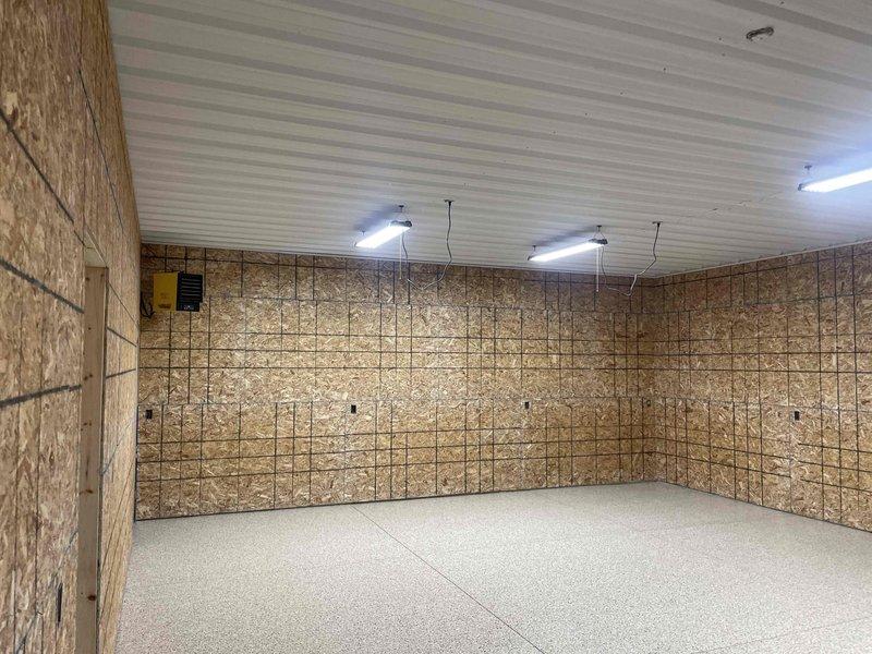 Conducted site evaluation for new mini-split system installation in finished garage/workshop space with OSB wall panels, corrugated metal ceiling, and epoxy-coated flooring. Assessed installation requirements and documented conditions for ductless heat pump system placement, noting wall construction, ceiling access points, and optimal locations for indoor air handler and outdoor condenser unit routing.