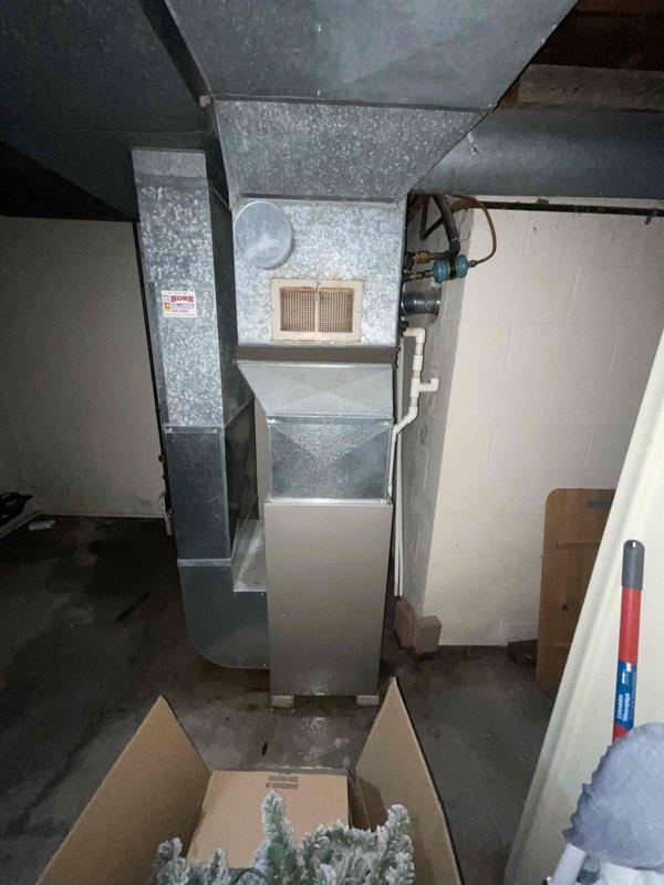 Completed whole-home air conditioning system estimate for replacement of aging outdoor condenser unit and indoor furnace system. Assessed existing equipment showing significant weathering and age-related deterioration on exterior condenser with corroded protective cage and overgrown vegetation at base. Documented indoor furnace installation in basement utility area with existing ductwork configuration and PVC condensate drainage. Provided comprehensive replacement recommendations to address immediate cooling needs per customer's request for expedited installation timeline.