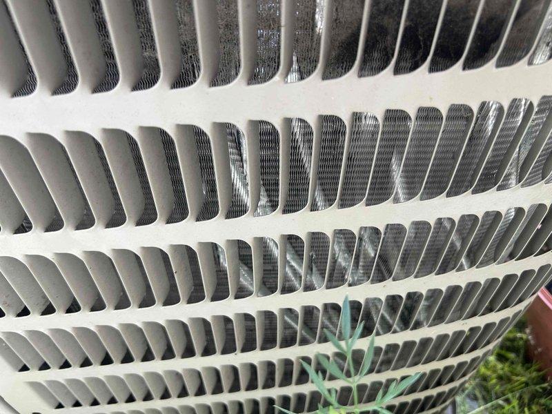 Responded to service call for air conditioning system not cooling adequately. Upon arrival, performed visual inspection of outdoor condensing unit and documented existing conditions. Condenser coils showed moderate dirt and debris accumulation in lower sections with organic matter collected at base of unit. Exterior fins appeared relatively clean on upper sections but internal heat exchanger components displayed dust buildup affecting airflow efficiency. Captured photographic documentation of condenser coil condition and overall unit status for service records. Customer requested refrigerant recharge; however, proper diagnostic protocol requires system performance testing and leak detection before adding refrigerant to determine root cause of insufficient cooling.