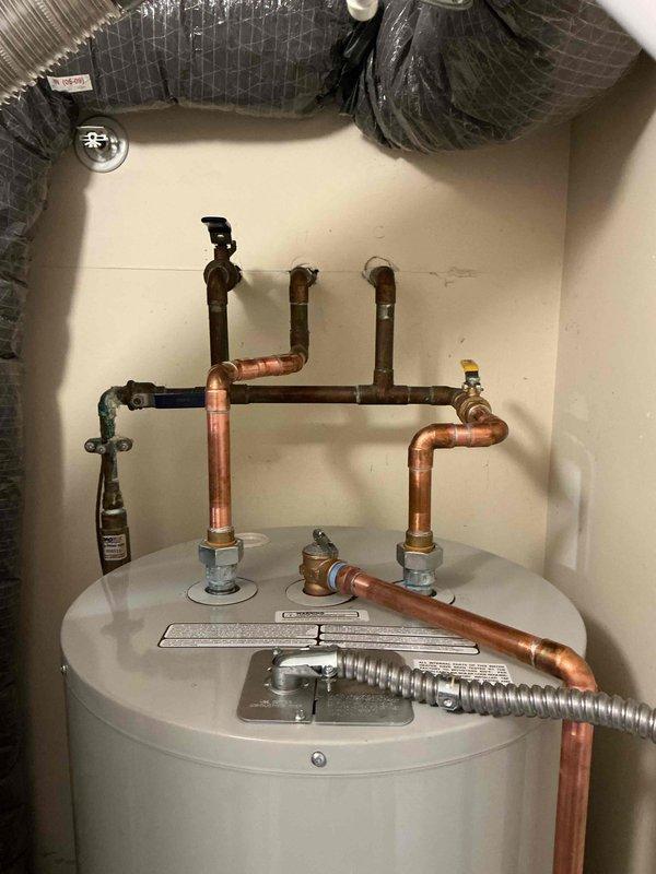 Completed installation of a 50-gallon electric tanked water heater in utility room. Established all copper supply line connections with appropriate shutoff valves, installed pressure relief valve with discharge piping, and connected electrical service through dedicated disconnect box with flexible metal conduit. Verified proper operation of all plumbing connections, tested temperature and pressure relief valve functionality, and confirmed electrical connections meet code requirements.