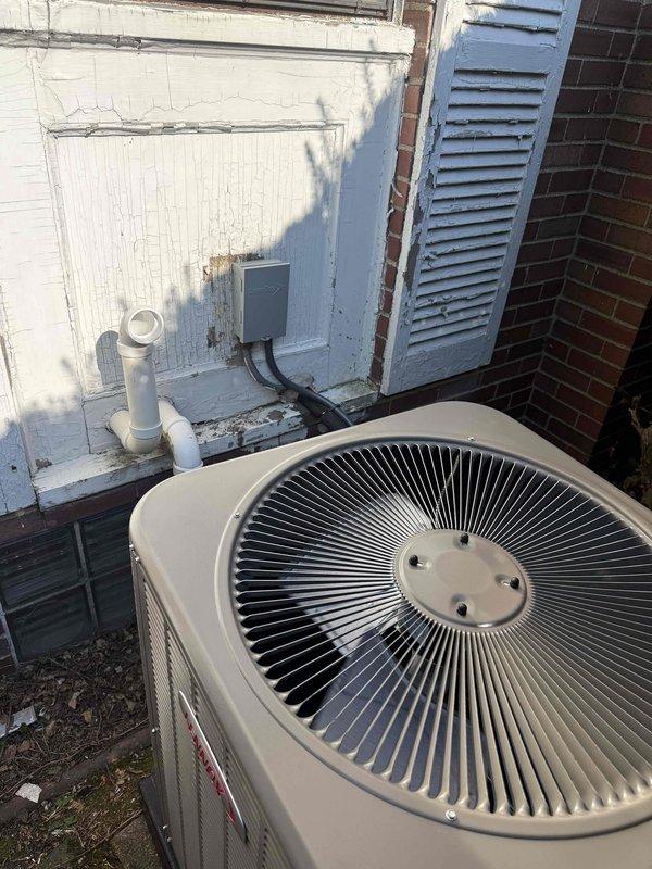 Completed installation of 3-ton air conditioning system with evaporator coil at residential property. Outdoor condenser unit positioned on left side of building with proper electrical connections and conduit installation, while indoor air handler and coil installed in basement mechanical room adjacent to existing water heater. All refrigerant lines connected, electrical wiring completed, system tested and operational upon completion.