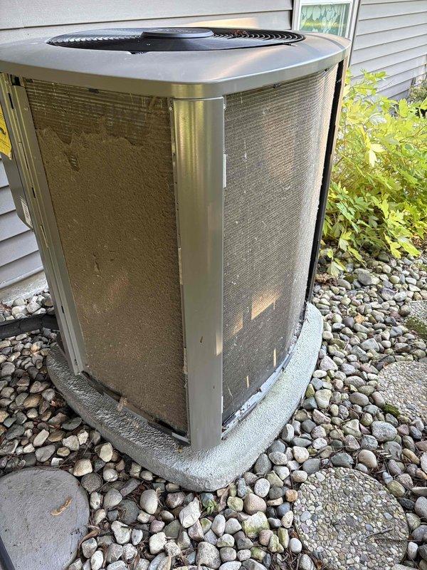 Completed annual air conditioning maintenance on residential outdoor condenser unit. Performed comprehensive inspection of heat exchanger coils, verified proper airflow through mesh grilles, and confirmed unit operation on stable concrete pad with adequate clearance from landscaping. All components found in functional condition with normal weathering appropriate for outdoor installation.