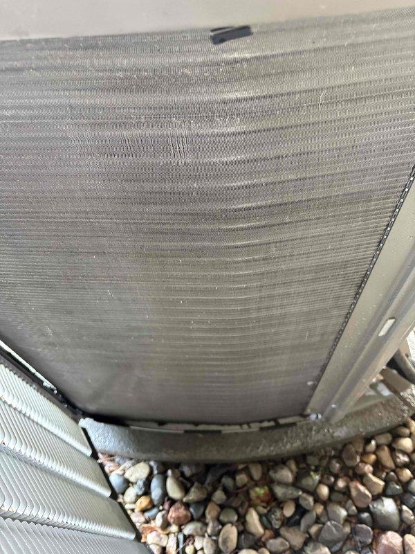 Completed annual air conditioning maintenance on residential outdoor condenser unit. Performed comprehensive inspection of heat exchanger coils, verified proper airflow through mesh grilles, and confirmed unit operation on stable concrete pad with adequate clearance from landscaping. All components found in functional condition with normal weathering appropriate for outdoor installation.