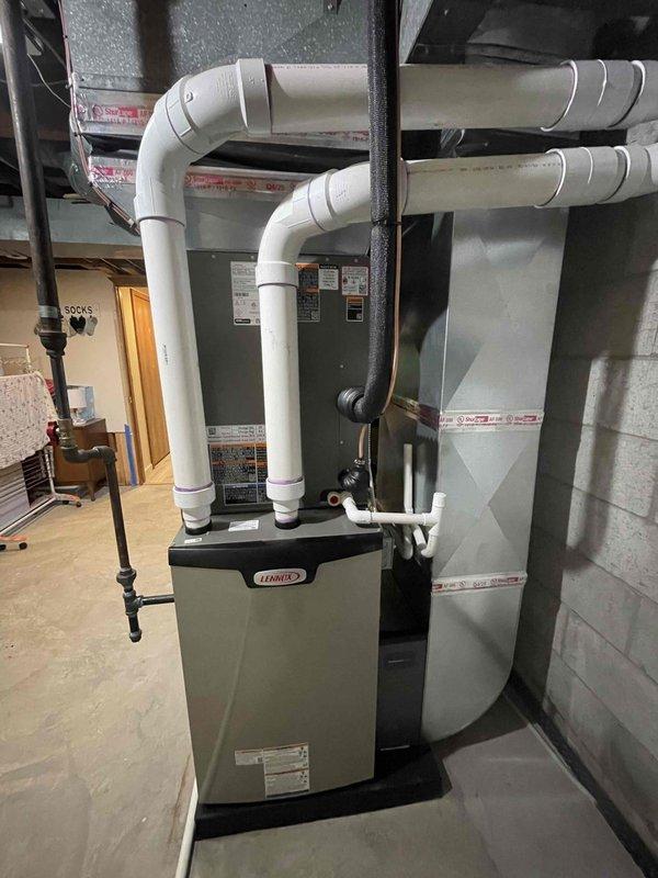 Completed full HVAC system installation including a Lennox 90,000 BTU high-efficiency furnace (model EL297UH090XV36CK), 3.5-ton air conditioning unit (model EL19KC1-042-230), and evaporator coil (model CK40CT-48C-71) in basement mechanical room. Installed PVC venting system with horizontal runs secured to wall, reconnected existing ductwork, integrated humidifier into system, and established proper condensate drainage. All equipment mounted on platform against concrete block wall with electrical connections completed and system tested for proper operation.