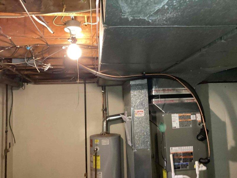 Completed installation of 2.5-ton air conditioning system with evaporator coil at residential property. Outdoor condensing unit positioned on platform at rear of home with proper electrical connections and refrigerant lines run to indoor air handler. Indoor evaporator coil installed in basement mechanical room and connected to existing ductwork, with all components tested and operational upon completion.