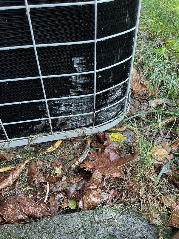 Performed diagnostic evaluation on 28-year-old residential air conditioning system. Unit was reported as still operational and providing cooling despite its age well beyond typical equipment lifespan. Conducted visual inspection of outdoor condensing unit, noting accumulated debris around base and significant rust staining on adjacent brick wall indicating potential historical moisture issues or oxidation from metal components. Verified system operation and confirmed unit continues to function. Documented current condition of aging equipment with photographic records showing wear patterns on protective grille, leaf accumulation at base, and overall unit placement. System remains operational but age indicates replacement should be considered in near-term planning.