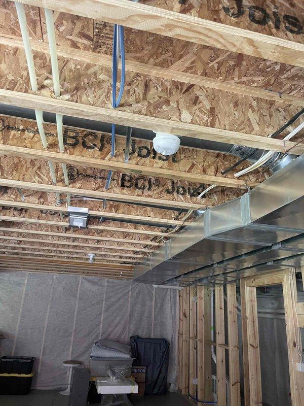 Completed on-site evaluation for backup generator installation at new home construction. Assessed electrical infrastructure requirements for Kohler generator system integration. Documented existing electrical panel location, available service capacity, and optimal generator placement options. Evaluated transfer switch installation requirements and determined necessary load calculations for whole-house backup power configuration. Photographed unfinished interior spaces showing exposed ceiling joists, OSB sheathing, existing HVAC ductwork routing, and wall framing to identify potential conduit pathways and equipment mounting locations. Reviewed structural considerations for exterior generator pad placement and fuel line routing. Prepared comprehensive estimate for complete automatic standby generator system installation including transfer switch, electrical connections, and code-compliant integration with existing service.