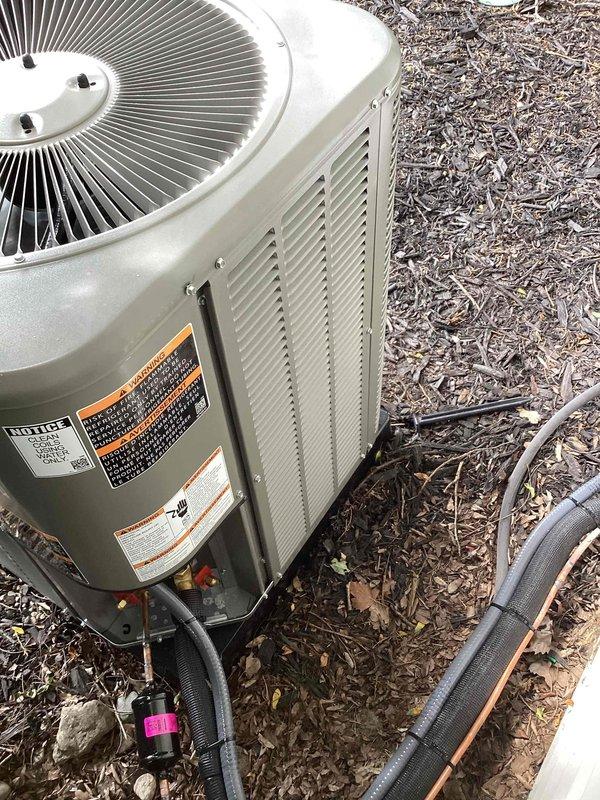 Completed full HVAC system installation including new furnace and 2-ton air conditioning condenser unit. Installed outdoor AC unit on right side of property with proper refrigerant line connections, electrical hookup, and conduit routing through mulched area. System positioned on prepared pad with all refrigerant lines insulated and secured, obtained mechanical permit for installation, and reconnected electrical service per code requirements.