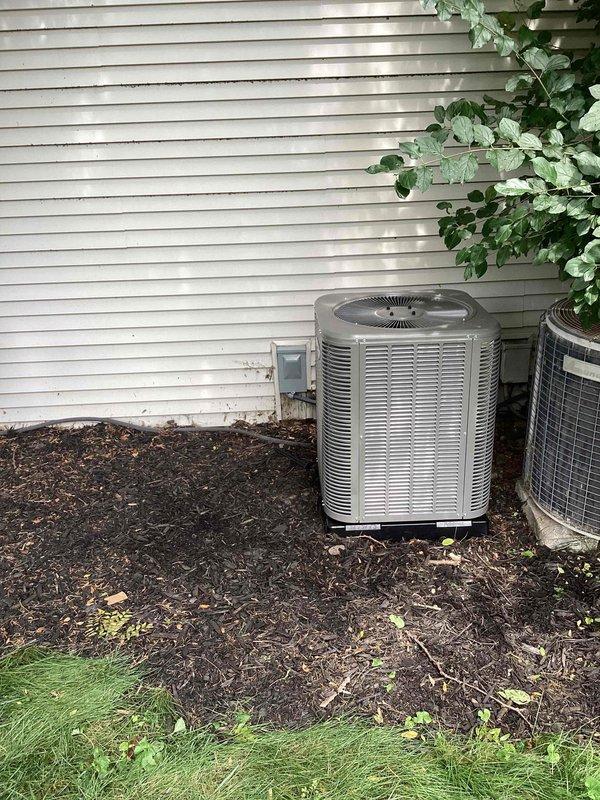 Completed full HVAC system installation including new furnace and 2-ton air conditioning condenser unit. Installed outdoor AC unit on right side of property with proper refrigerant line connections, electrical hookup, and conduit routing through mulched area. System positioned on prepared pad with all refrigerant lines insulated and secured, obtained mechanical permit for installation, and reconnected electrical service per code requirements.