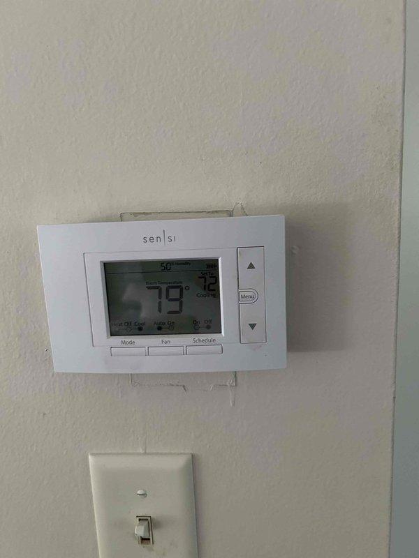 Responded to service call for newly purchased home with reported inadequate cooling performance on 1-year-old Lennox HVAC system. Upon arrival, found Sensi thermostat set to 50°F in cooling mode with ambient temperature reading 79°F, indicating improper thermostat programming. Inspected indoor air handler and furnace unit located in basement utility area; verified all mechanical components, refrigerant lines, and condensate drainage system operating within normal parameters. Provided thermostat operation tutorial, demonstrated proper temperature setpoint adjustment, mode selection, and scheduling functions. Inspected filter cage accessibility as requested and confirmed filter removal process. Verified system operation under proper settings; unit cooling effectively once thermostat correctly programmed. Checked water heater status per homeowner request. System under parts and labor warranty coverage.